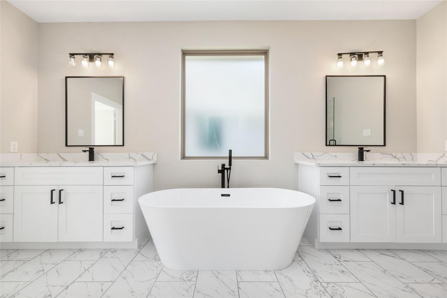 This expansive primary bathroom offers a sleek, modern design with a luxurious freestanding soaking tub, featuring a pure white finish accented by bold black details. The dual sinks, each with ample storage, provide plenty of space for daily routines. Elegant marble-like flooring complements the neutral color palette, while abundant natural light fills the room, creating a bright and inviting atmosphere perfect for relaxation and self-care.