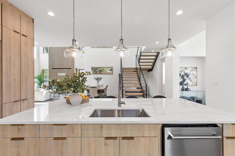 Kitchen featuring light brown cabinetry, sink, and light stone counters