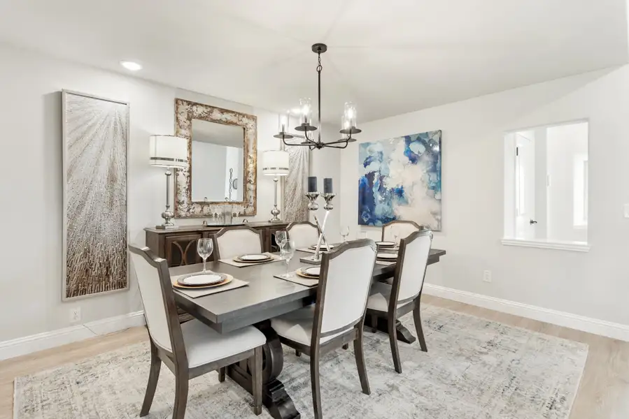 Formal dining room with dark wood table, six upholstered chairs, chandelier, and decorative wall art