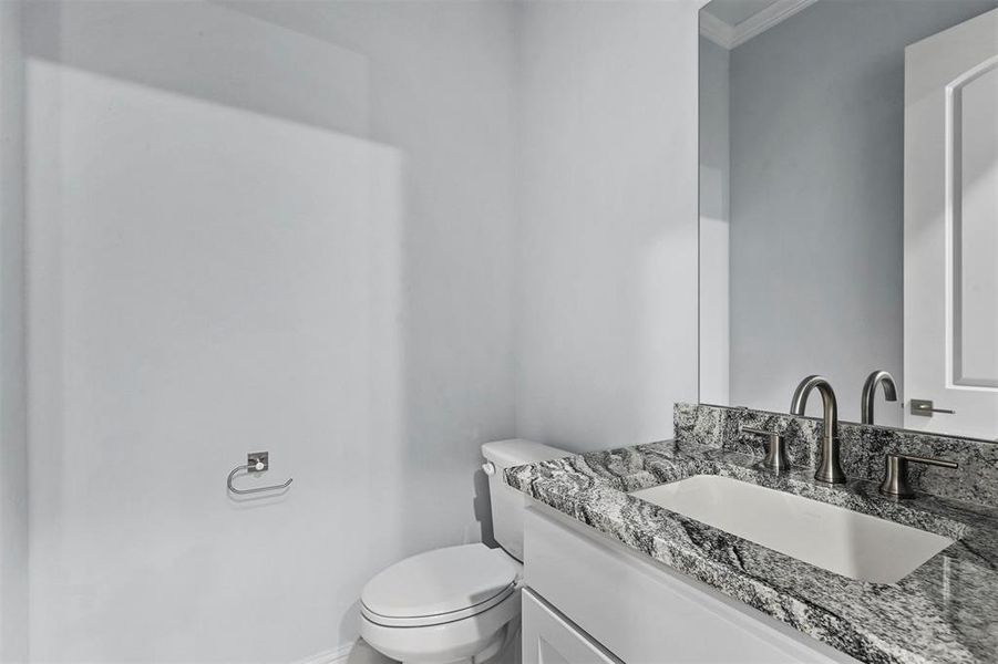 Bathroom featuring toilet, crown molding, and vanity