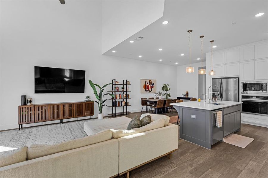 Kitchen with open floor plan, appliances with stainless steel finishes, pendant lighting, a kitchen island with sink, and gray cabinetry