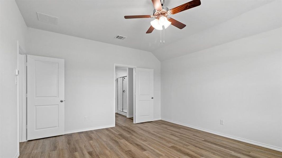 Spacious room with wood-finish flooring and a vaulted ceiling Spacious room with wood-finish flooring and a vaulted ceiling