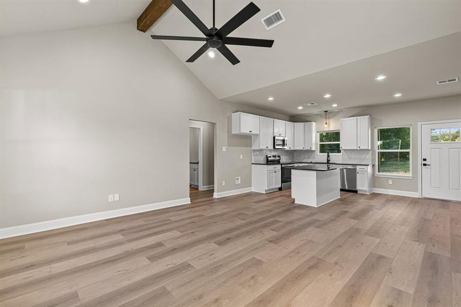 Kitchen featuring dark countertops, open floor plan, beamed ceiling, recessed lighting, and white cabinetry Kitchen featuring dark countertops, open floor plan, beamed ceiling, recessed lighting, and white cabinetry