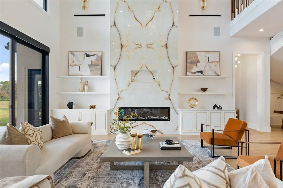 Indulge in luxury in your living room, featuring two story ceilings and a marble-clad fireplace that stretches from floor to ceiling, adding a touch of opulence to your space.