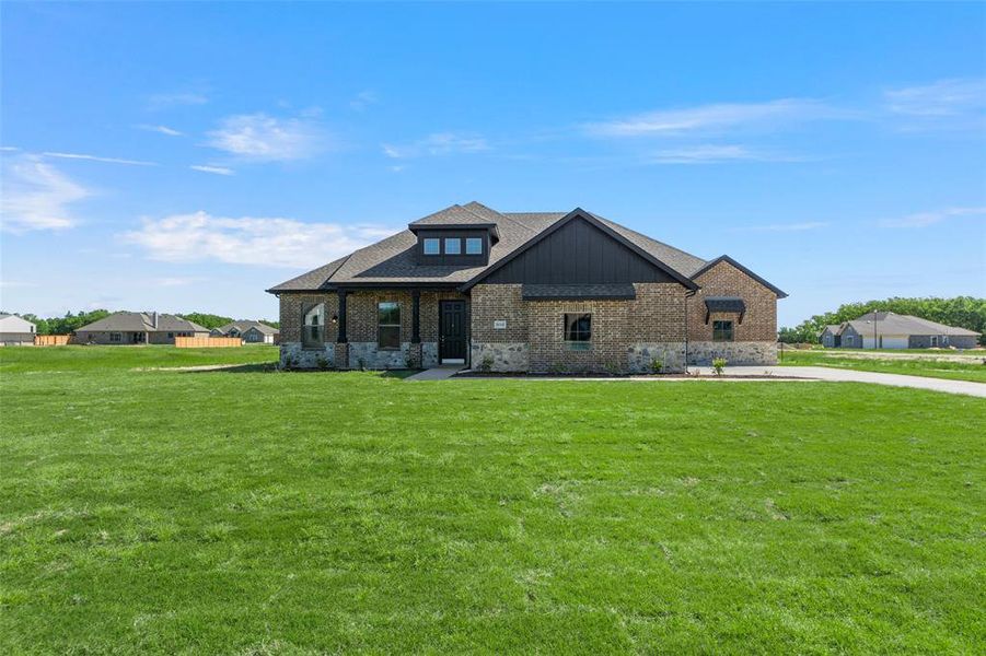 View of front of house with brick siding, a front lawn, and roof with shingles