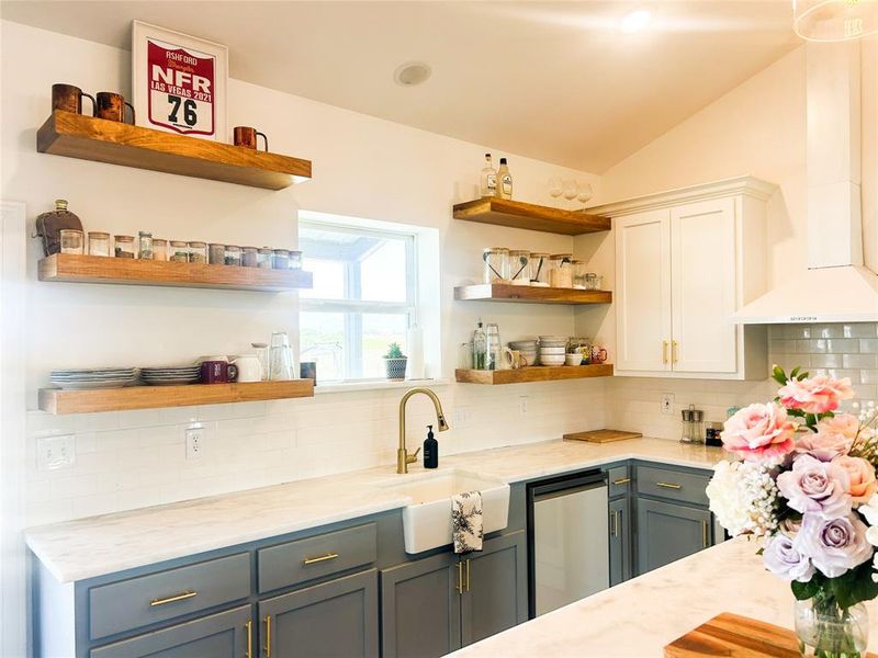 Kitchen featuring tasteful backsplash, open shelves, light stone counters, lofted ceiling, and white cabinets Kitchen featuring tasteful backsplash, open shelves, light stone counters, lofted ceiling, and white cabinets