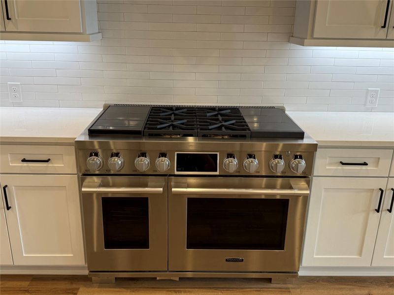 48" Stainless steel range looks great and cooks better with propane burners.  White subway tile backsplash and under cabinet lighting make for a bright work area.