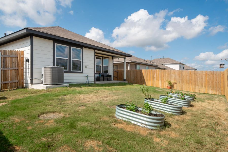 Back of property featuring a patio area, a fenced backyard, and a vegetable garden