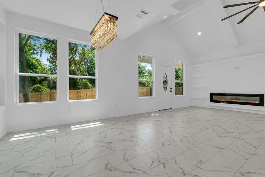 Unfurnished living room with a wealth of natural light, high vaulted ceiling, and light tile patterned floors