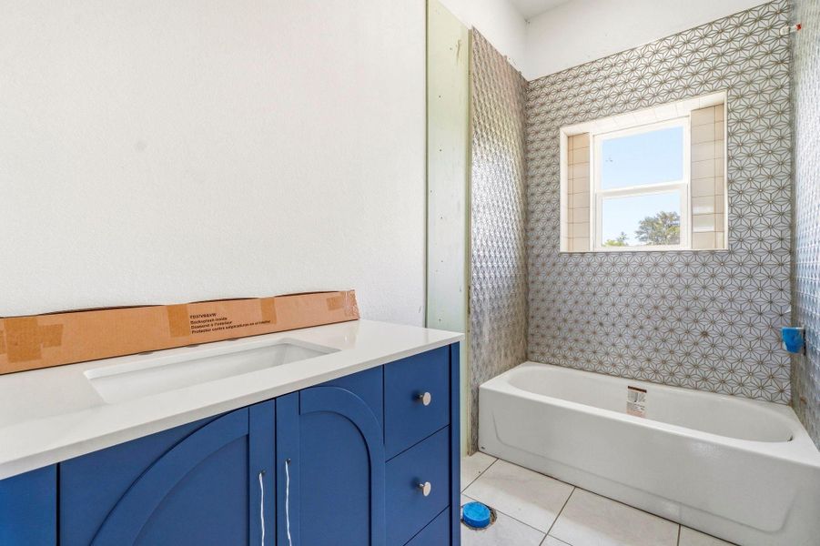 Secondary bathroom features a tub/shower combo beautifully finished with tile surround and a stylish sink vanity, offering both function and tasteful design.
