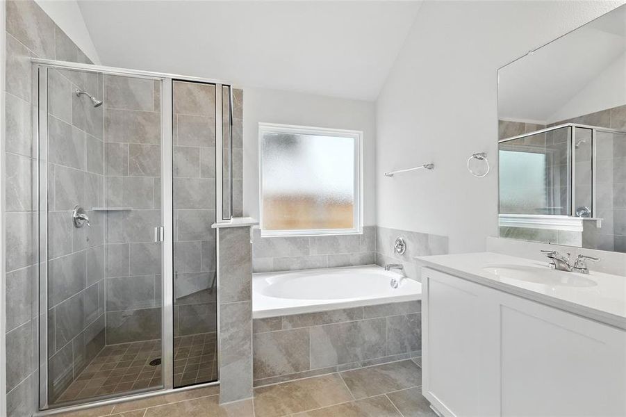 Bathroom with lofted ceiling, vanity, a garden tub, a stall shower, and tile patterned floors Bathroom with lofted ceiling, vanity, a garden tub, a stall shower, and tile patterned floors