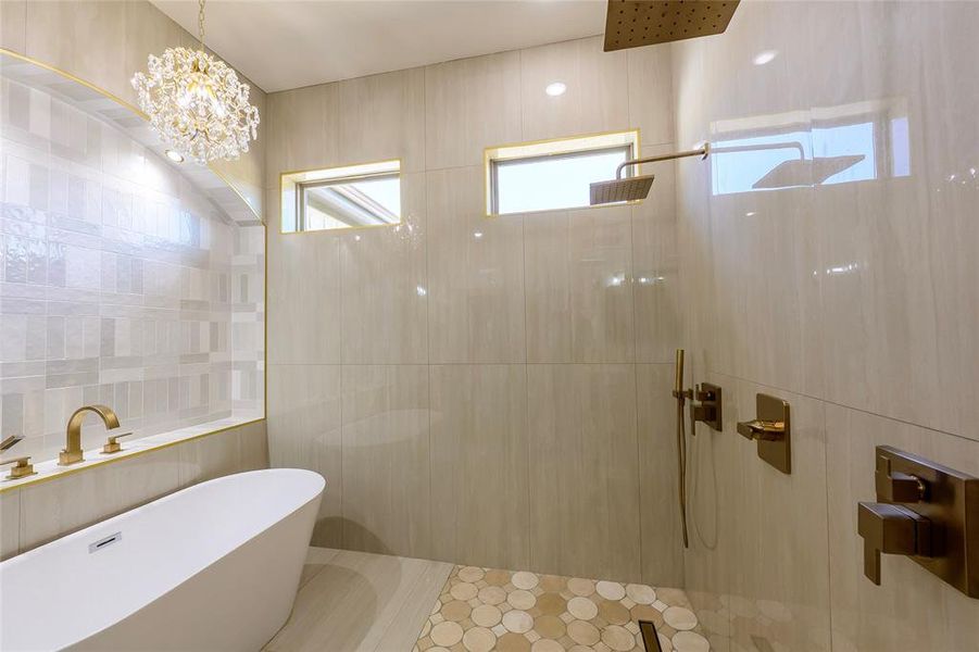Bathroom featuring tile walls, a walk in shower, a soaking tub, and hanging lights Bathroom featuring tile walls, a walk in shower, a soaking tub, and hanging lights