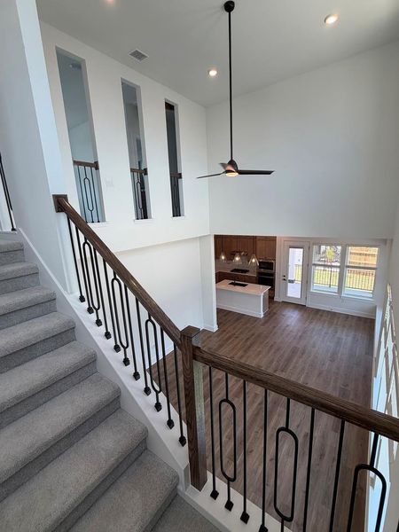 An inviting open-concept layout unfolds from the carpeted stairway, revealing a sleek kitchen and bright living space below. An inviting open-concept layout unfolds from the carpeted stairway, revealing a sleek kitchen and bright living space below.