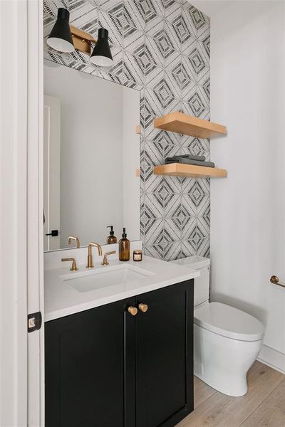 Modern vanity featuring a white countertop, gold-finish faucet, and black cabinetry with gold-finish knobs Modern vanity featuring a white countertop, gold-finish faucet, and black cabinetry with gold-finish knobs