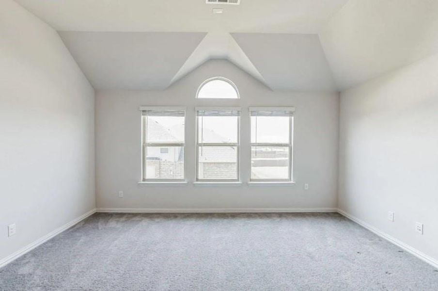 Carpeted spare room with vaulted ceiling