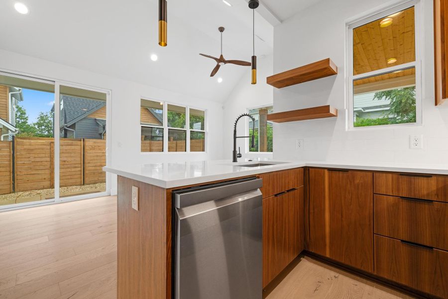 Kitchen featuring dishwasher, modern cabinets, a peninsula, light wood-style floors, and vaulted ceiling Kitchen featuring dishwasher, modern cabinets, a peninsula, light wood-style floors, and vaulted ceiling