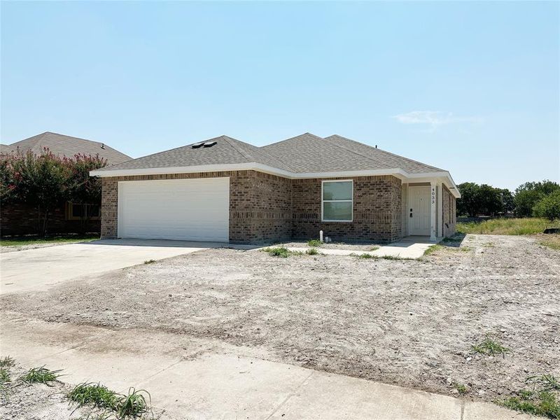 Single story home with roof with shingles, brick siding, driveway, and an attached garage
