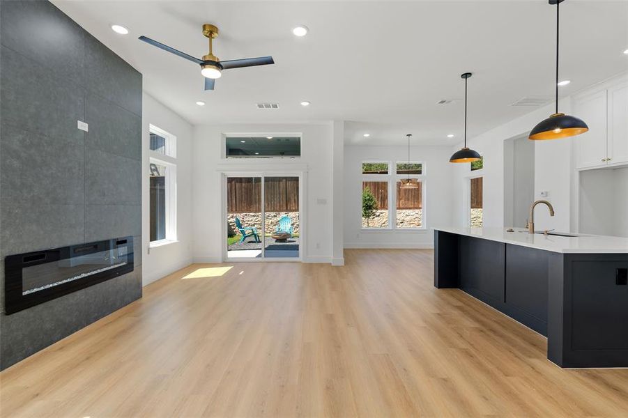 Unfurnished living room with ceiling fan, sink, light hardwood / wood-style floors, and a large fireplace