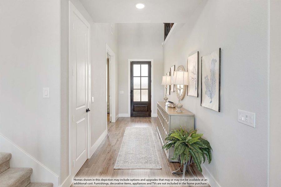Hallway with hardwood floors, runner rug, console table, and glass-panel front door at the end