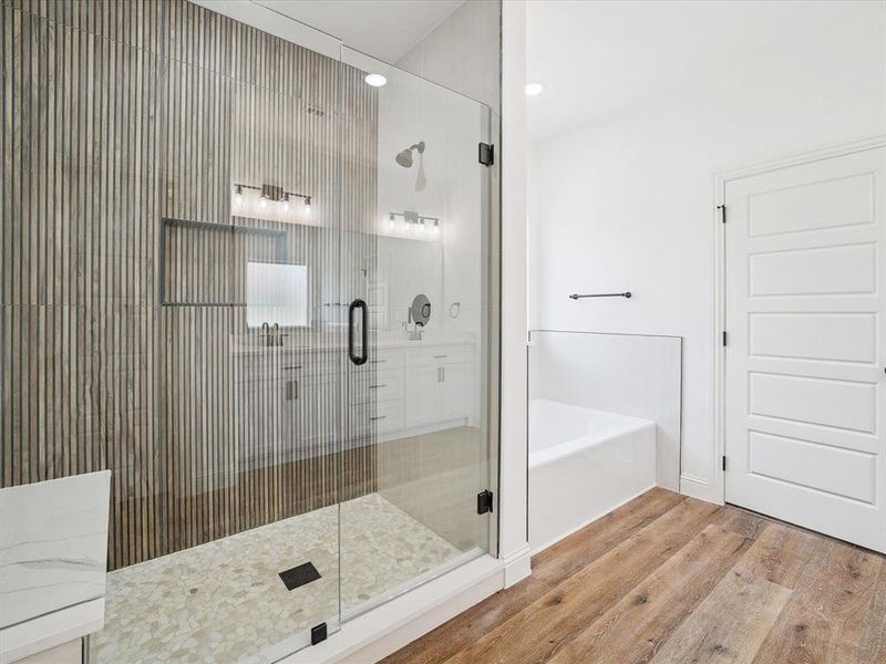 Bathroom featuring a shower stall, a garden tub, and light wood-style flooring