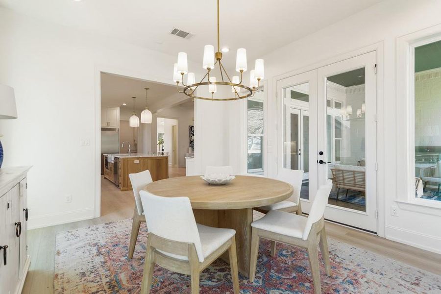 Dining space with french doors, a chandelier, and light wood-style flooring