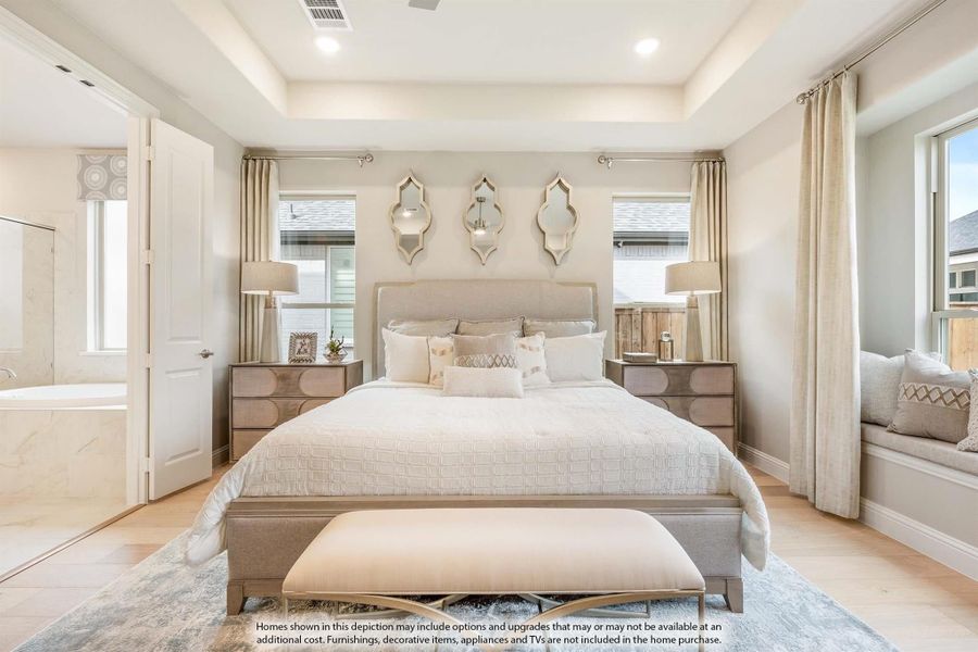 Master bedroom with tray ceiling, hardwood floors, and ensuite bathroom access