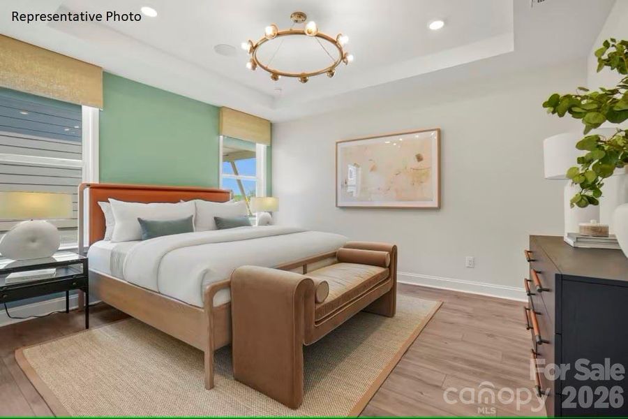 Luxurious primary bedroom features EVP flooring and tray ceiling