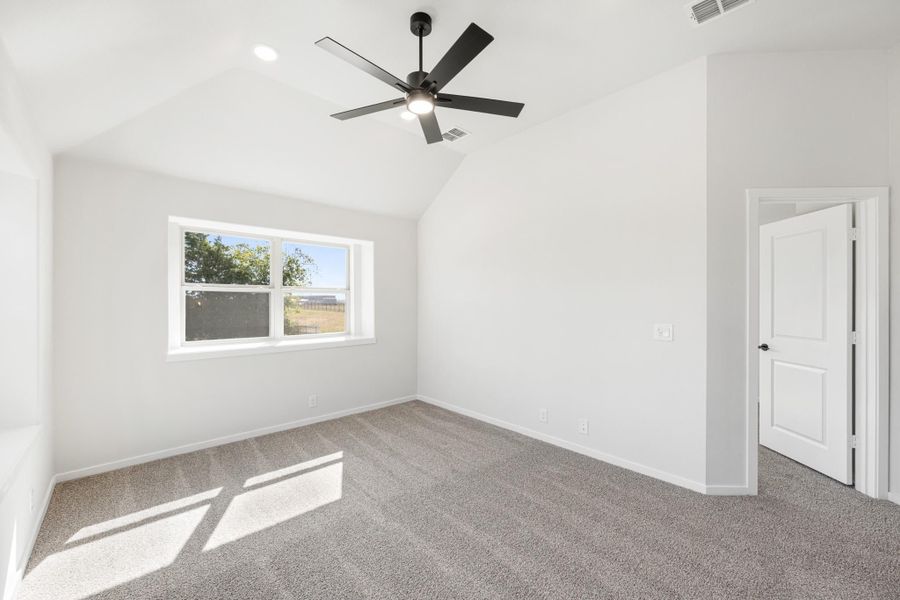 Empty bedroom with vaulted ceiling, black ceiling fan, gray carpet, and a single window