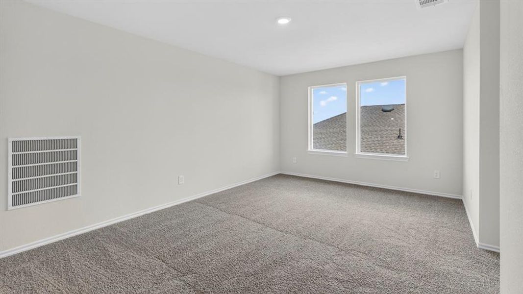 Spacious room featuring neutral carpeting, light gray walls, two bright windows, and a recessed ceiling light