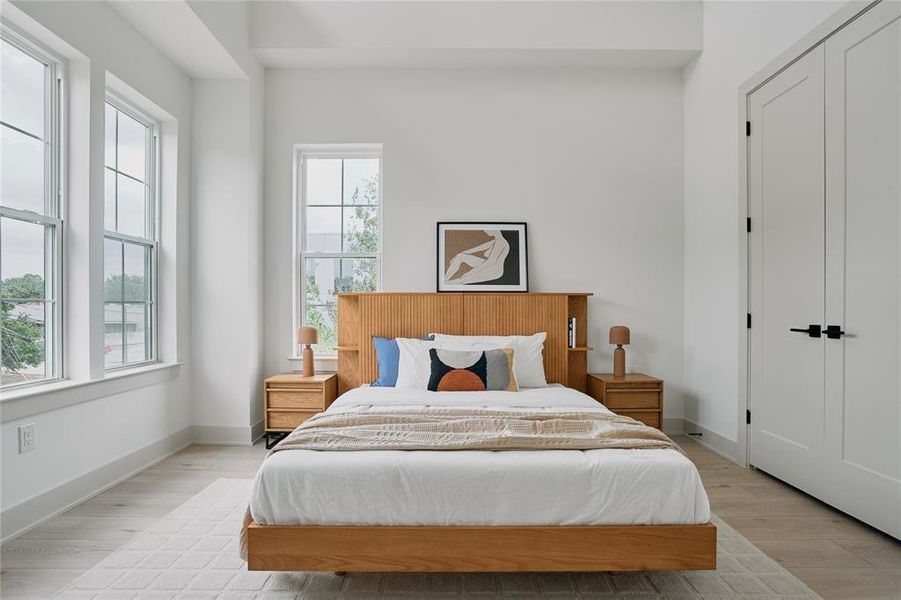 Bright room with tall ceilings, light wood-finish flooring, and white walls