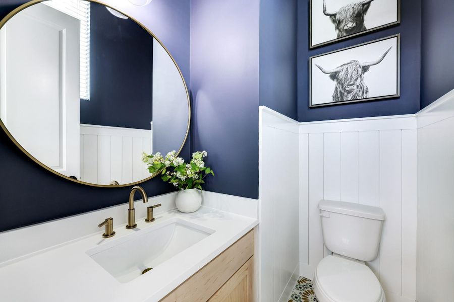 Chic Powder Room: Featuring elegant navy walls, a sleek white vanity, and striking gold accents, this stylish half bath adds a touch of sophistication to your home. Chic Powder Room: Featuring elegant navy walls, a sleek white vanity, and striking gold accents, this stylish half bath adds a touch of sophistication to your home.