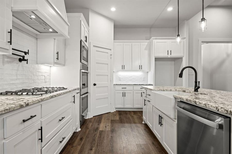 Kitchen featuring stainless steel appliances, white cabinetry, and custom exhaust hood