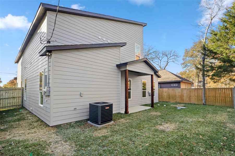 Back of house with a yard and central air condition unit