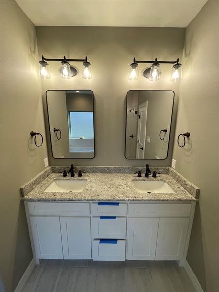 Full bathroom featuring double vanity and wood finished floors
