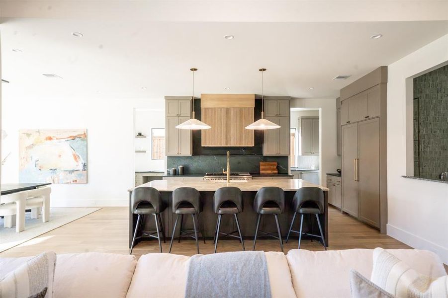 Kitchen with pendant lighting, backsplash, a center island with sink, light hardwood / wood-style flooring, and gray cabinets