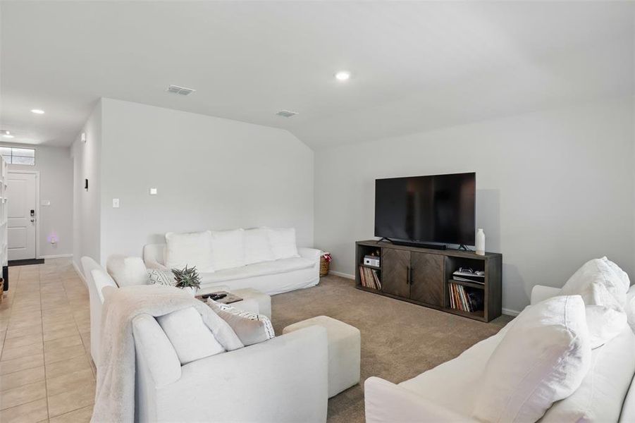 The living room has a loft ceiling, recessed lighting, and light tile patterned floors.