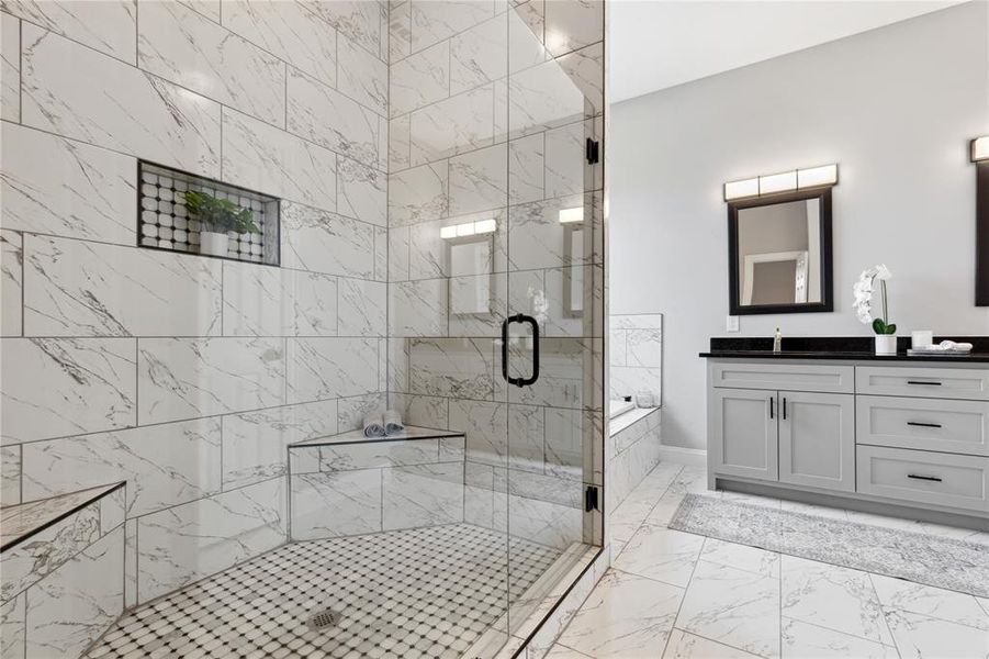 Bathroom featuring a stall shower, marble finish floor, vanity, and a garden tub