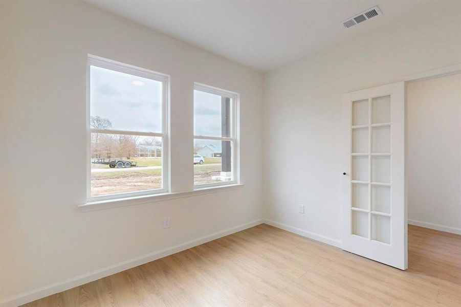 Unfurnished room featuring visible vents, light wood-type flooring, and baseboards