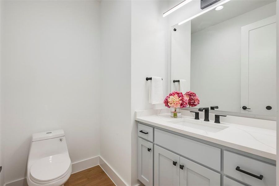 Powder bathroom with vanity and light wood-type flooring Powder bathroom with vanity and light wood-type flooring