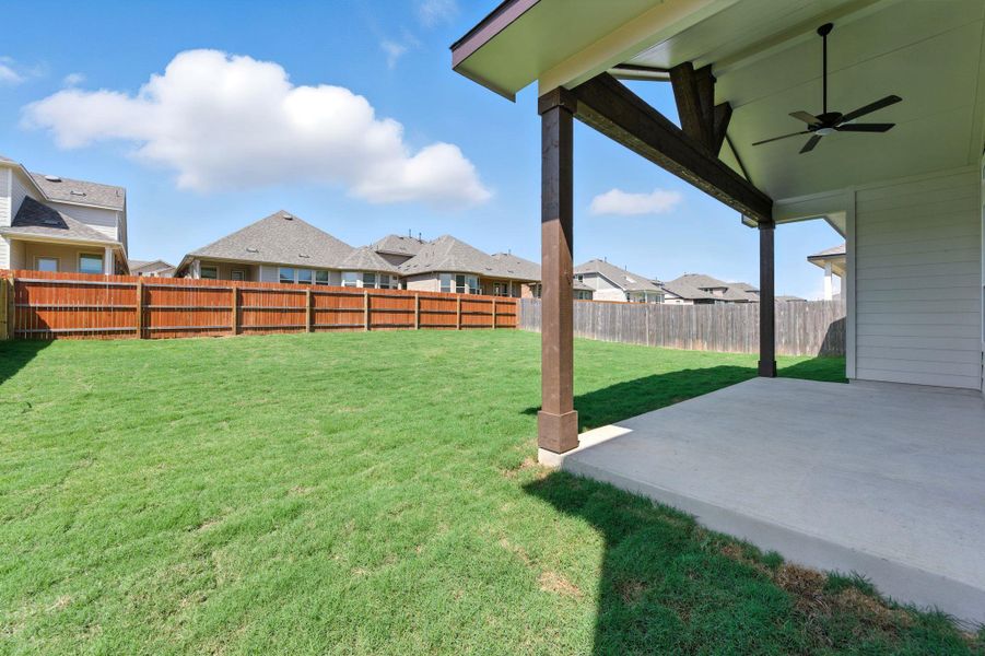 Fenced backyard featuring a residential view, ceiling fan, and a patio area
