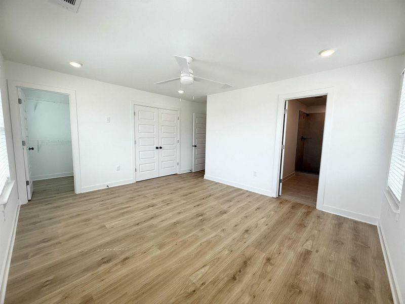 Unfurnished bedroom featuring light wood-style flooring, recessed lighting, ensuite bathroom, a ceiling fan, and two closets