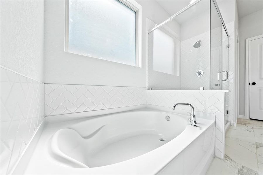 Primary en suite bathroom with garden tub, separate showers, dual vanity