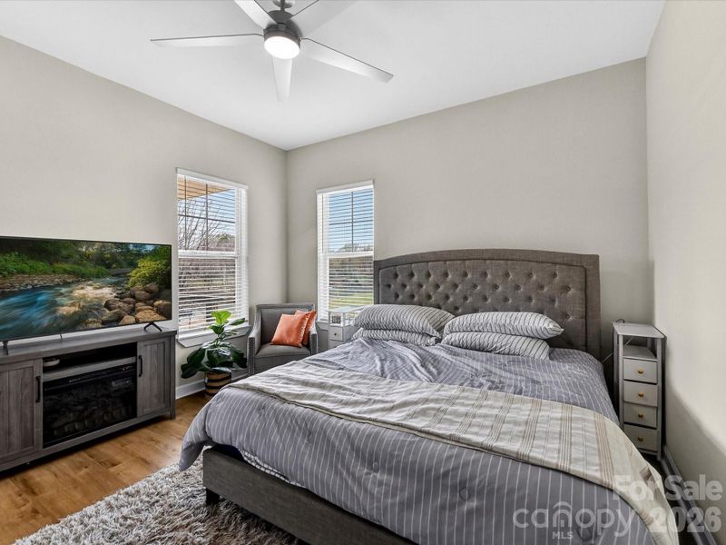 Bright and inviting bedroom featuring neutral tones, a ceiling fan/light and convenient access to a private ensuite bathroom.