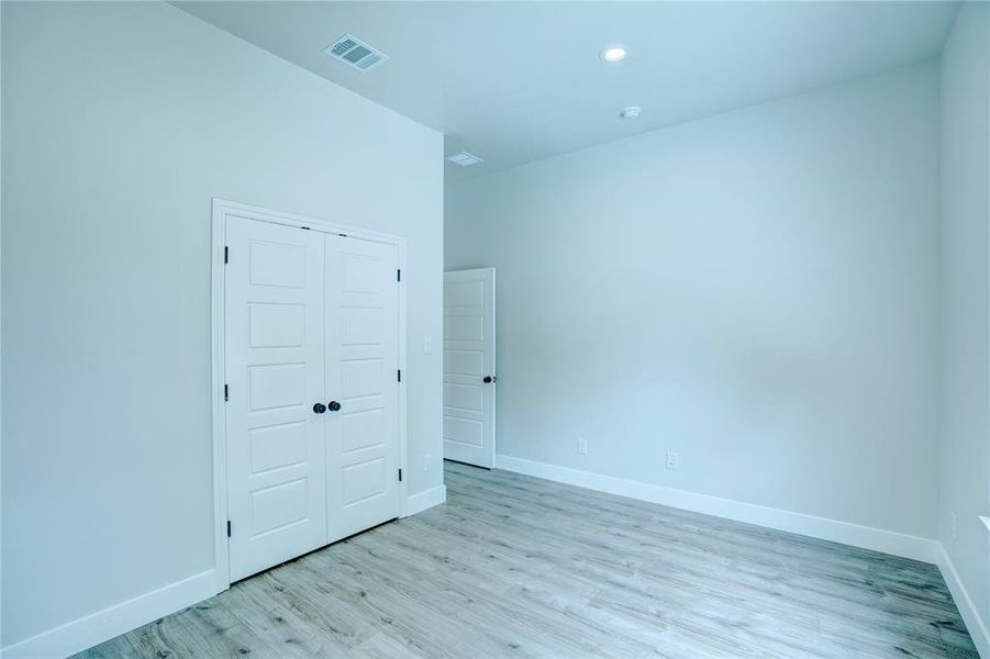 Interior room featuring wood-finish flooring, white baseboards, and light-colored walls