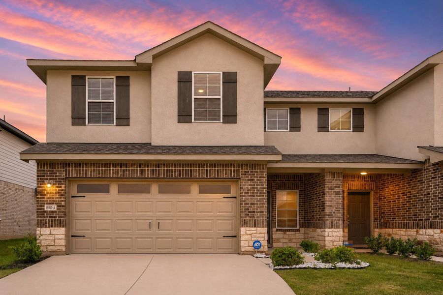 Two-story residential exterior featuring a stucco and brick facade with stone accents Two-story residential exterior featuring a stucco and brick facade with stone accents