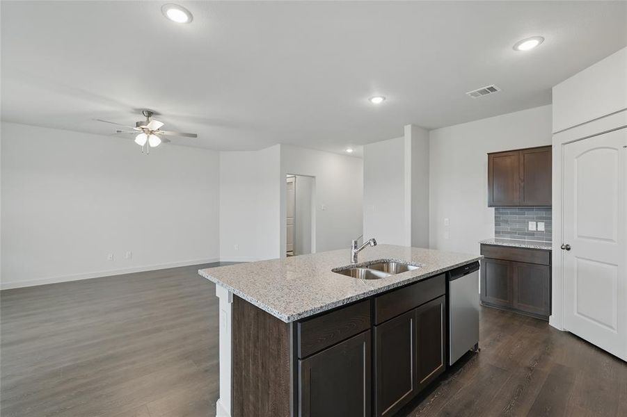 Kitchen featuring light stone countertops, a ceiling fan, dark wood finished floors, a center island with sink, and recessed lighting Kitchen featuring light stone countertops, a ceiling fan, dark wood finished floors, a center island with sink, and recessed lighting