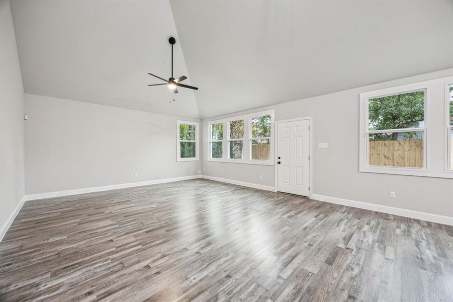Family room featuring lofted ceiling, light wood-style flooring lots of windows, and a ceiling fan