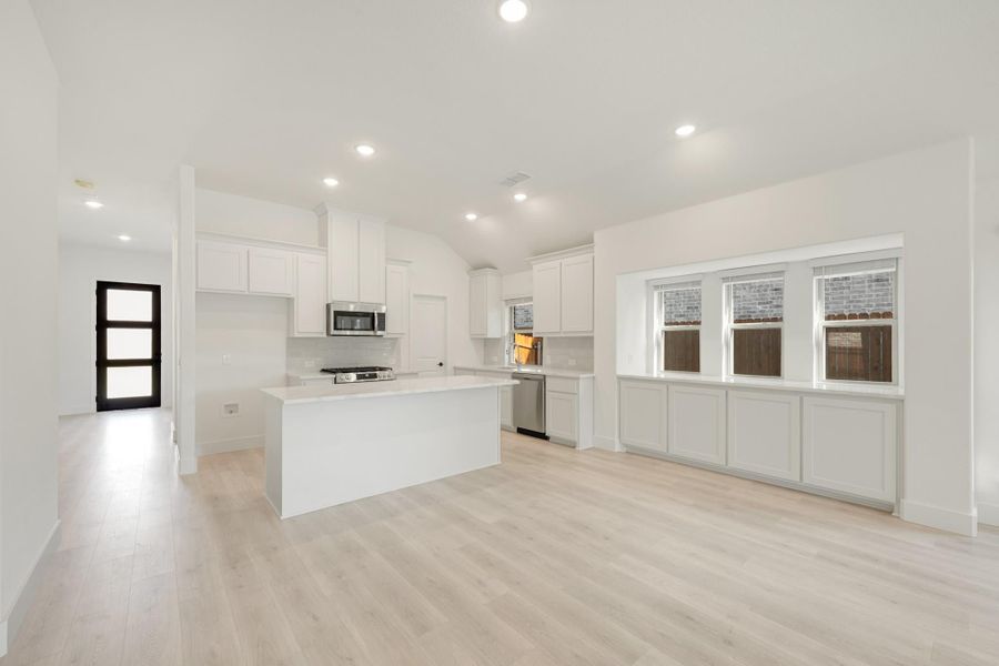 Open kitchen with white cabinets, center island, stainless appliances, and light wood floors Open kitchen with white cabinets, center island, stainless appliances, and light wood floors