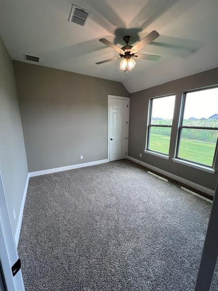 Unfurnished bedroom with ceiling fan, carpet flooring, and lofted ceiling