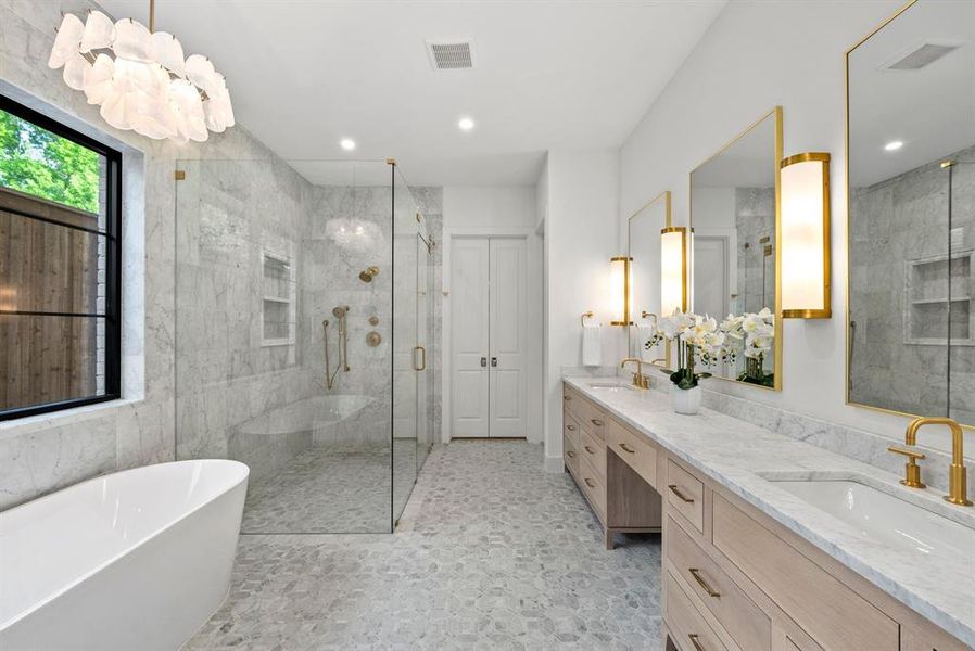 The bathroom features a freestanding tub, a large walk-in shower with a glass enclosure, and a double vanity with two sinks and gold-toned fixtures